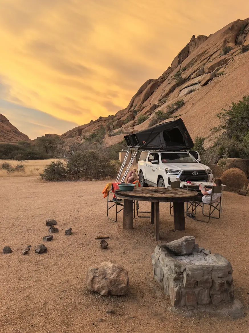 Toyota Hilux 4x4 driving through Namibian desert dunes at sunset